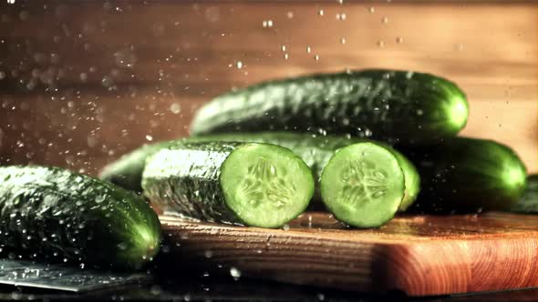 Drops of Water with Splashes Fall on Pieces of Fresh Cucumber alt