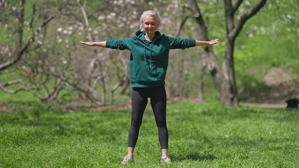 Wide Shot Front View of Fit Retiree Exercising Reaching Tiptoes with Hands alt