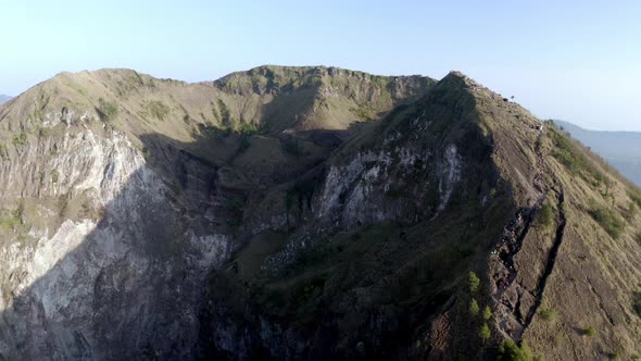 Mount Batur active volcano summit in Bali Indonesia with people visiting crater ridge, Aerial pan le alt
