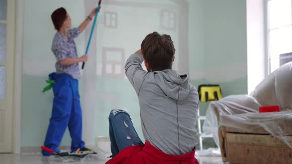 Back View Man Gesturing Talking to Blurred Woman Painting Wall in New Home alt