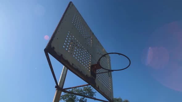 Rusty basketball hoop on inner city basketball court no net 4K alt