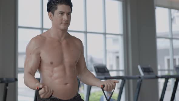 Athletic muscular man training with elastic band at a fitness alt