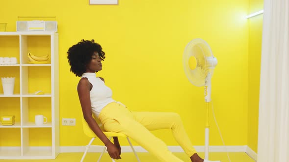 Woman Has Fun Sitting In Front of Fan alt