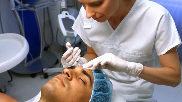 Doctor inserting facial injection on male patient forehead alt