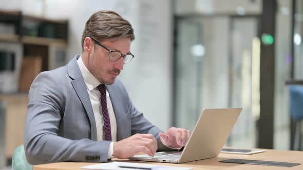 Businessman Working on Laptop in Office alt