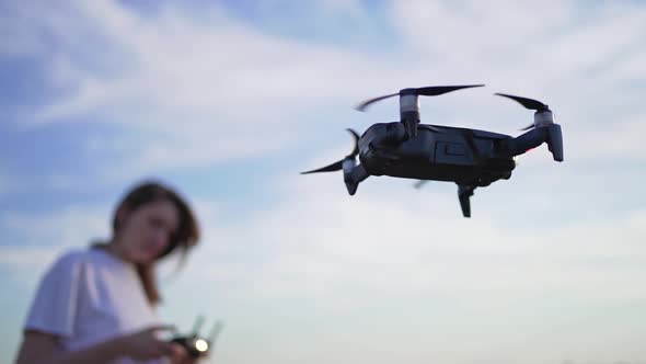 A Woman Controls the Flight of a Drone. The Quadcopter Hovered in the Air, the Female Drone Pilot