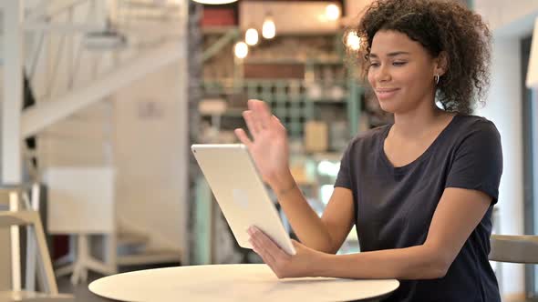 Online Video Chat on Tablet By Young African Woman in Cafe alt