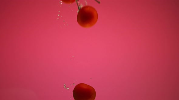 Red Pepper and Tomatoes Falling Into the Water with Bubbles in Slow Motion alt