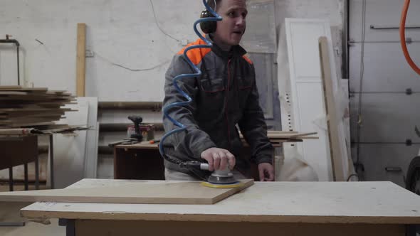 A Worker in the Furniture Industry Grinds Wood Products with a Grinder