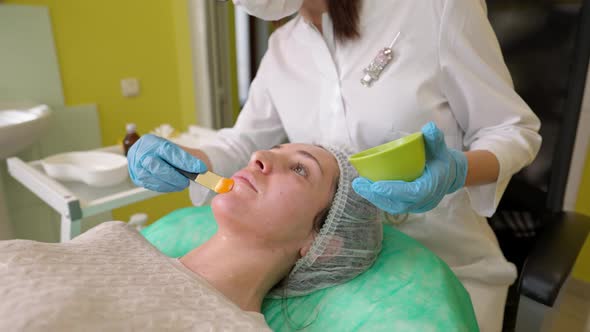 Female Cosmetologist Performing Fruit Acid Peeling Procedure for Young Women in Beauty Clinic alt