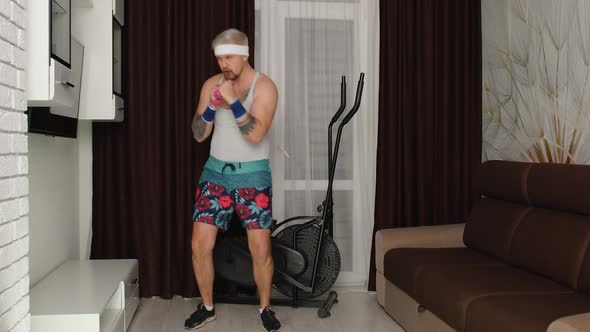 Sportsman Stylish Fat Guy in Funny Clothes Making Boxing Exercises with Dumbbells in Place at Home alt