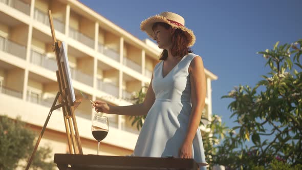 Focused Creative Caucasian Slim Woman Mixing Colors on Canvas with Painting Knife Outdoors alt