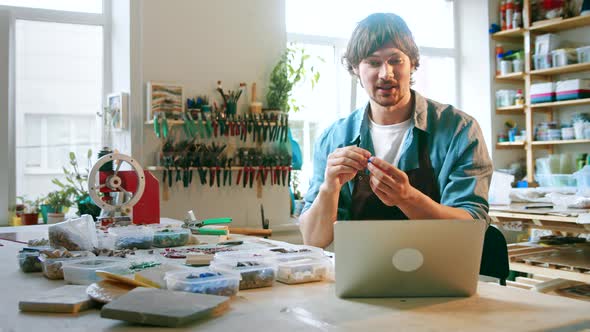 Young male in an apron talking by video call alt