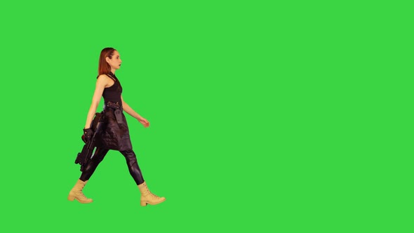 Cyber Girl Walks with Machine Gun in Hand on a Green Screen Chroma Key