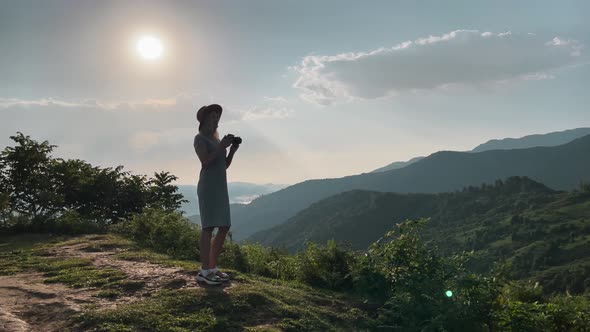 Photographer Takes a Pictures of a Mountains View on a Camera