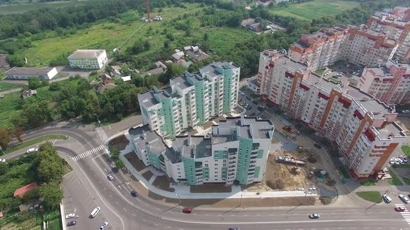Flying over the modern residential buildings and green trees in the town. alt
