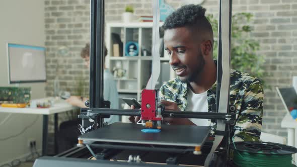 African American Guy Using 3D Printer in Office Enjoying Modern Technology alt