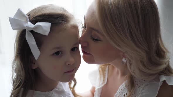Beautiful Family Mother and Daughter in White Dresses are Sitting on the Floor By Large Window alt