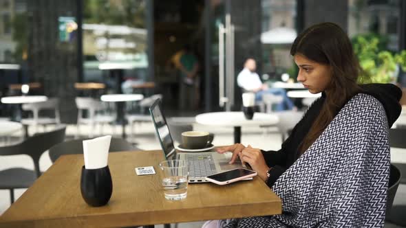 Female Student Using Netbook While Sitting in Cafe alt