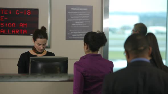 Airport passengers check in at ticket counter alt