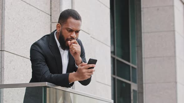 Frustrated Young African Man Looking at Smartphone Screen Feeling Disappointed with Received Bad alt