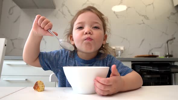 A Small Child Eats Healthy Food From a White Plate