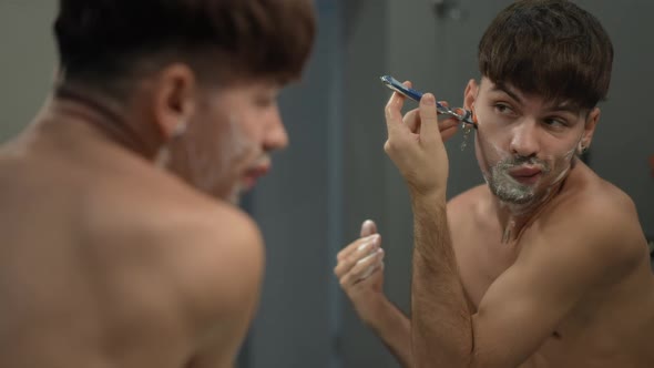 Young Man Shaving Goatee in Slow Motion in Bathroom at Home alt
