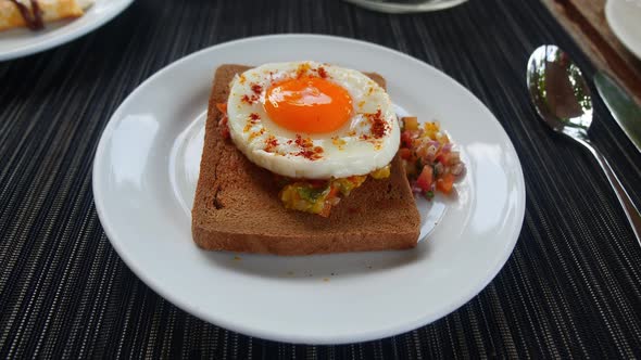 View From Above of a Toasted Whole Grain Bread with Raw Vegetables and Roasted Egg on a White Plate
