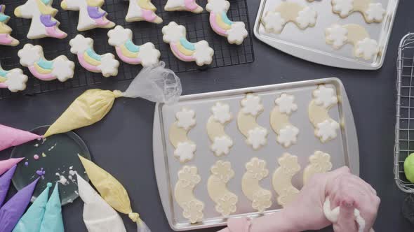 Step by step. Flat lay. Decorating unicorn theme sugar cookies with royal icing on baking sheet alt
