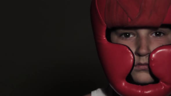 Young Guy boxer in a protective stance looks at the camera. Red helmet on head and bandages