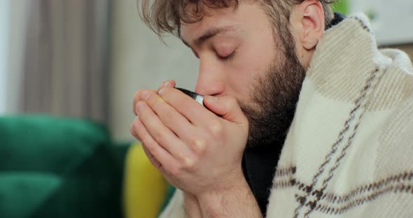 Sick Young Man Covered with Warm Blanket Got Flu Virus Caught Cold Drinking Hot Tea at Home alt