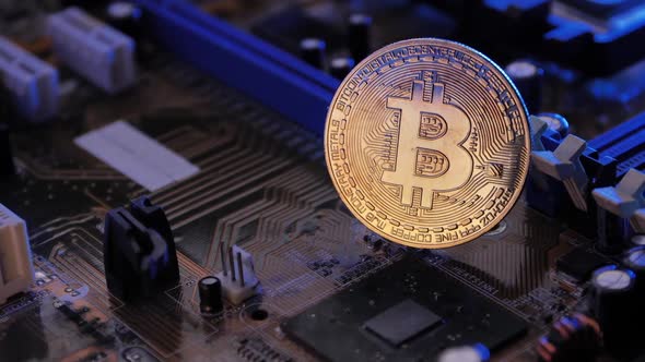 Golden coin with bitcoin symbol on electronic circuits in a computer mainboard. alt