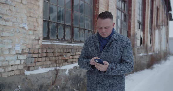 A Man Walks Down The Street Near The Old House And Talks On His Mobile With A Serious Expression