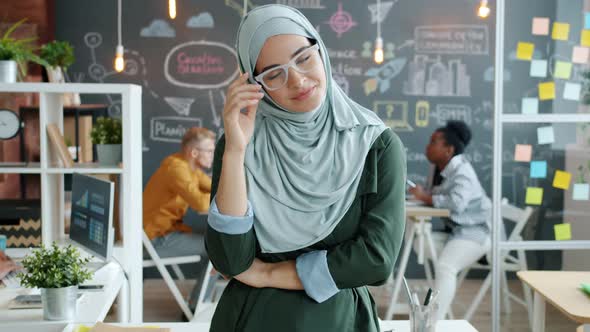 Portrait of Elegant Muslim Business Lady Taking Off Glasses Smiling Looking at Camera in Workplace alt