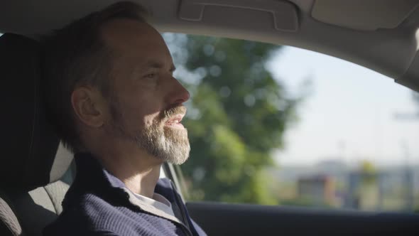 A Middleaged Handsome Caucasian Man Waits Relaxes and Thinks in a Car  Side Closeup