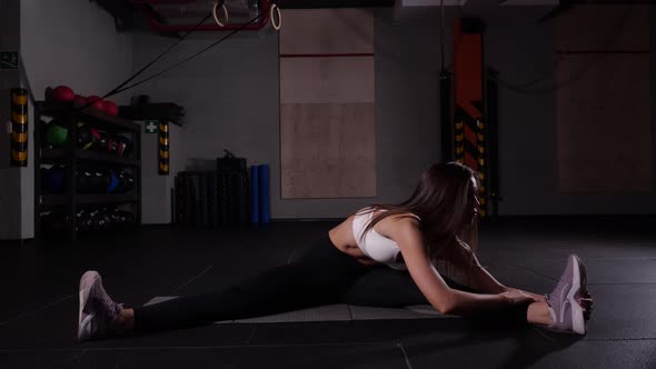 Slender Girl in Black Leggings and Purple Sneakers Does a Stretch in the Gym