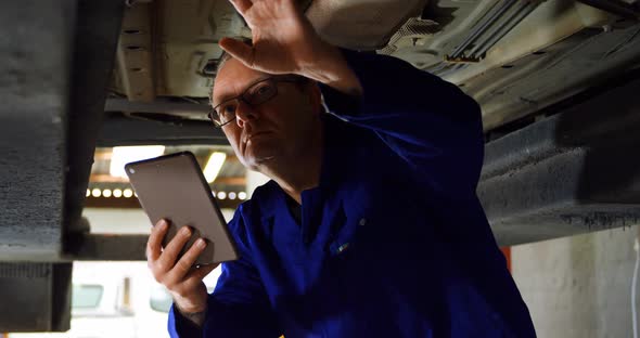 Mechanic using digital tablet while examining a car 4k alt