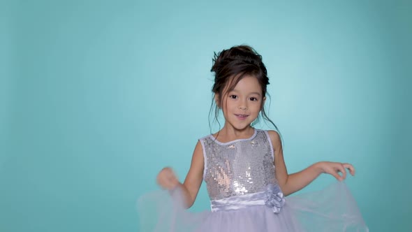 Beautiful Little Child Girl in Silver Dress Dancing on Blue Background