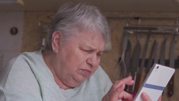 Concentrated Senior Woman Using Smartphone Scrolling On Screen