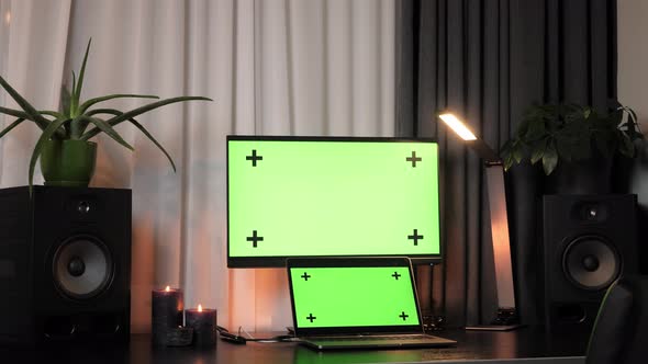 Interior of home office with desk, laptop and computer with mock-up green screen displays.  alt