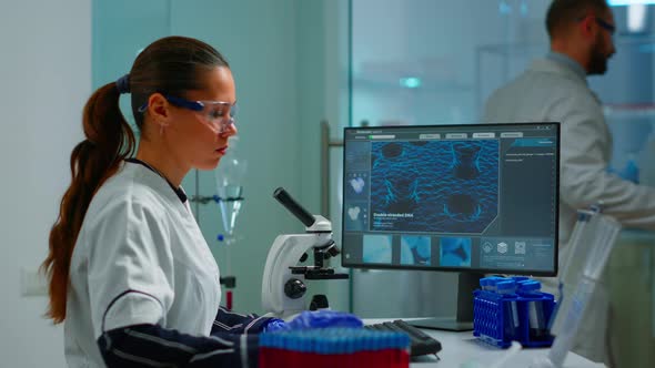 Biotechnology Scientist Researching in Laboratory Using Microscope alt