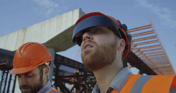 Builder in Goggles Speaking with Colleague alt