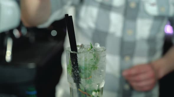 Process of preparing a Mojito cocktail with ice. Barman at work preparing cocktails. alt