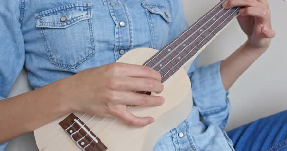 Woman play ukulele at home alt