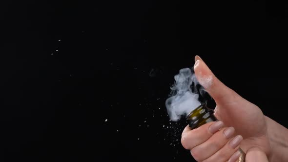 Female Hand Uncorking Bottle of Champagne on Black Background alt