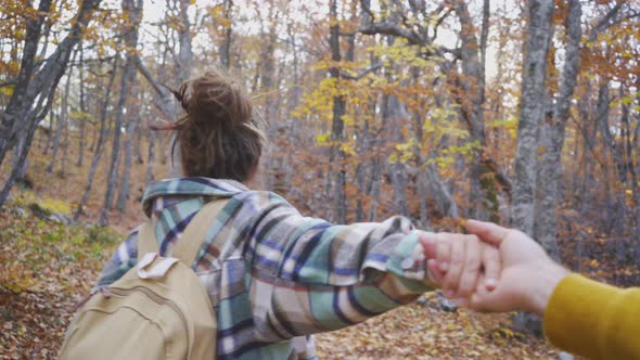 Happy Woman in Jacket Leads Friend By Hand Across Forest