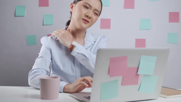 Asian woman working on a laptop was sick with body pain sitting