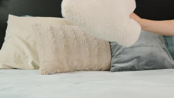 Woman Hand Put Pillow in Form of Large White Plush Cloud on Bed alt