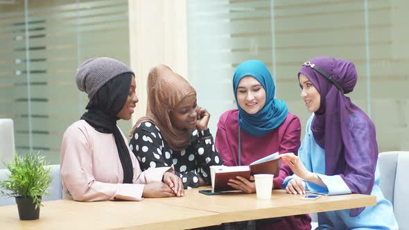 Happy Muslim Multiethnic Girls Students Discussing Book in Library alt