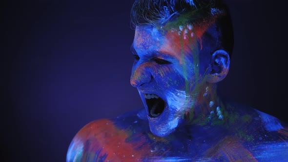 Portrait of Young Man in UV Paint He Screams with His Mouth Wide Open alt